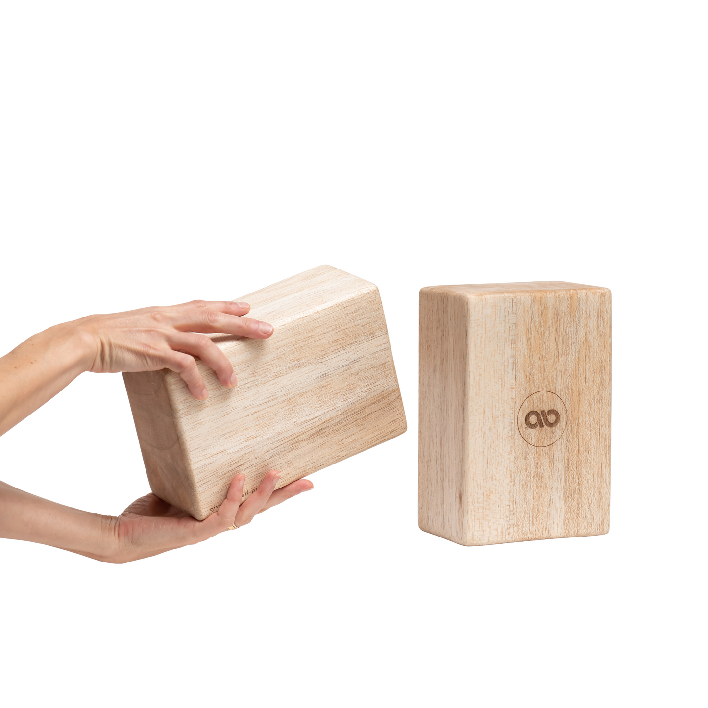 Pair of natural balsa wood yoga blocks shown on a white background with one block held by hands and one block standing upright. — for Carpe Diem Dream