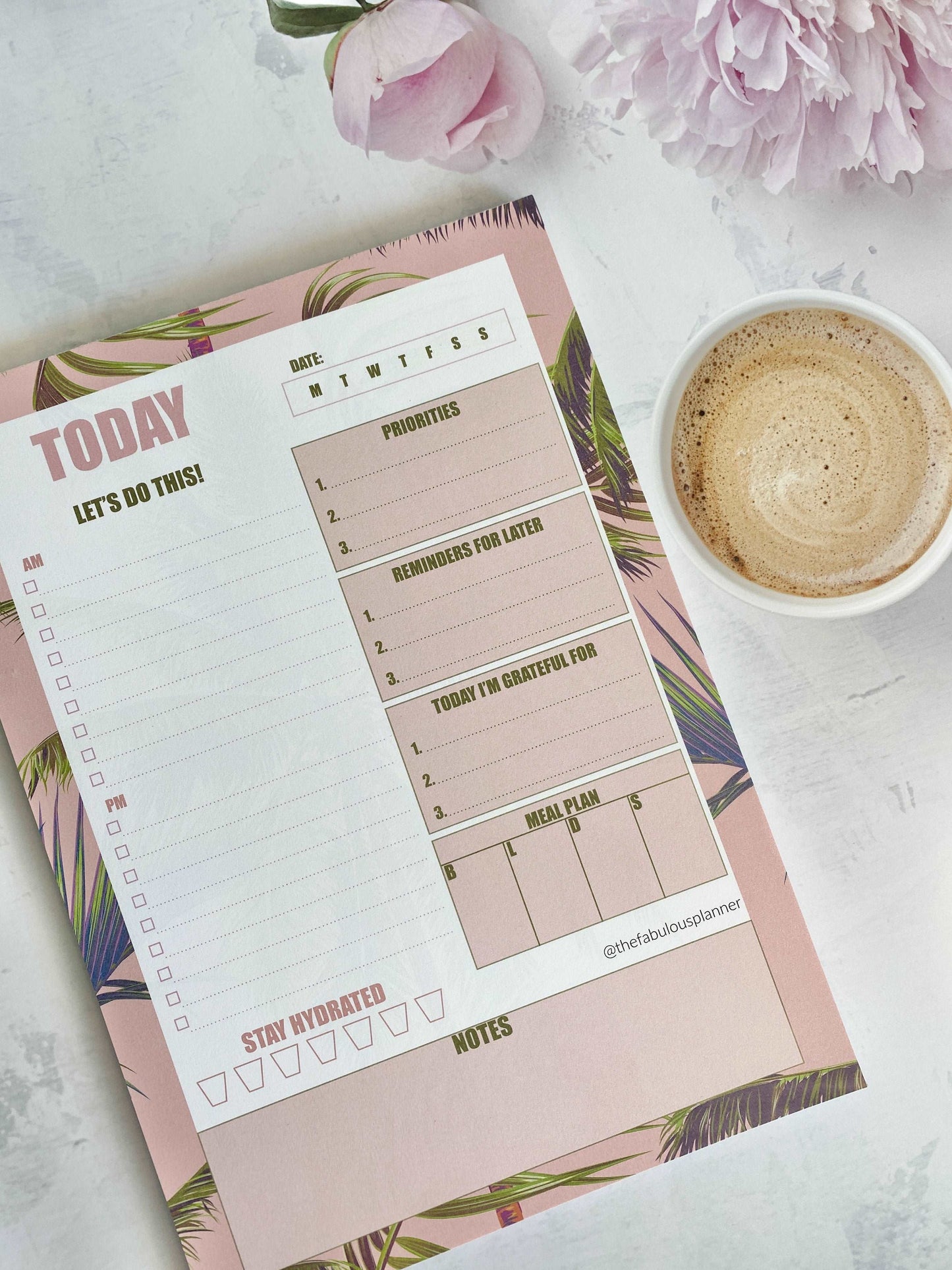 Pink tropical leaves 7x10 daily planner notepad styled on a marble surface with a latte and pink flowers in soft natural light — for Carpe Diem Dream