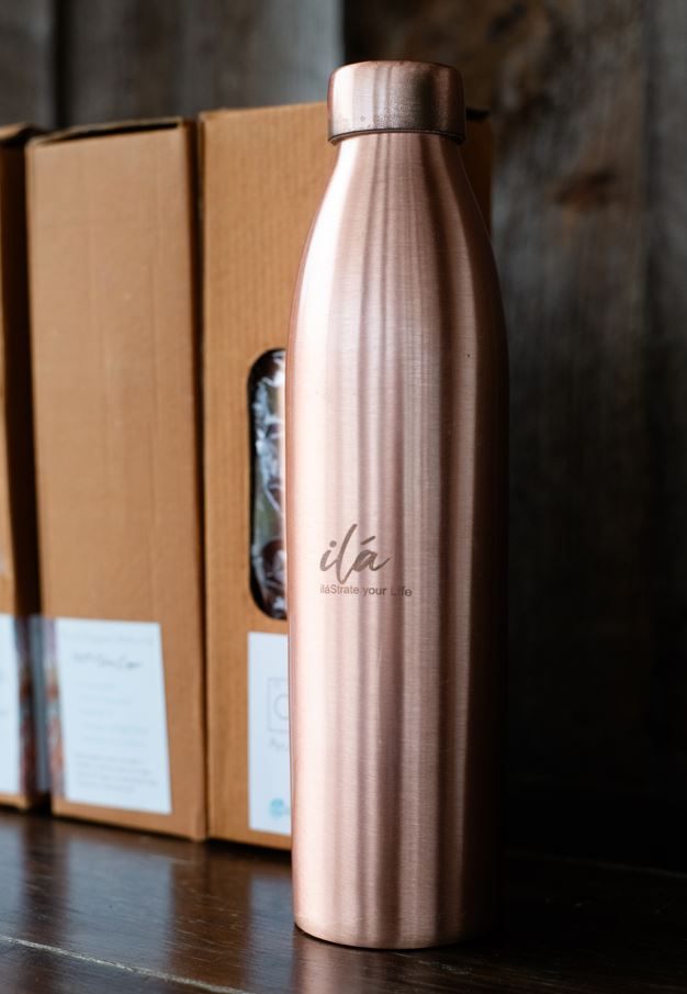 Rose-gold Ayurvedic copper water vessel displayed beside branded packaging boxes on a dark wooden surface. — for Carpe Diem Dream