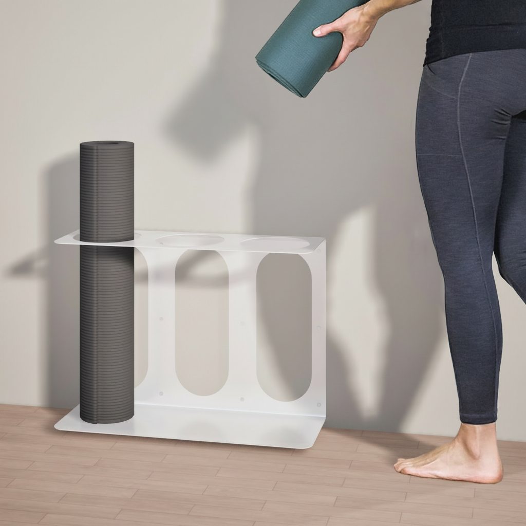 White metal yoga mat wall bracket holding a dark gray rolled yoga mat while a person places a green rolled yoga mat beside it. — for Carpe Diem Dream