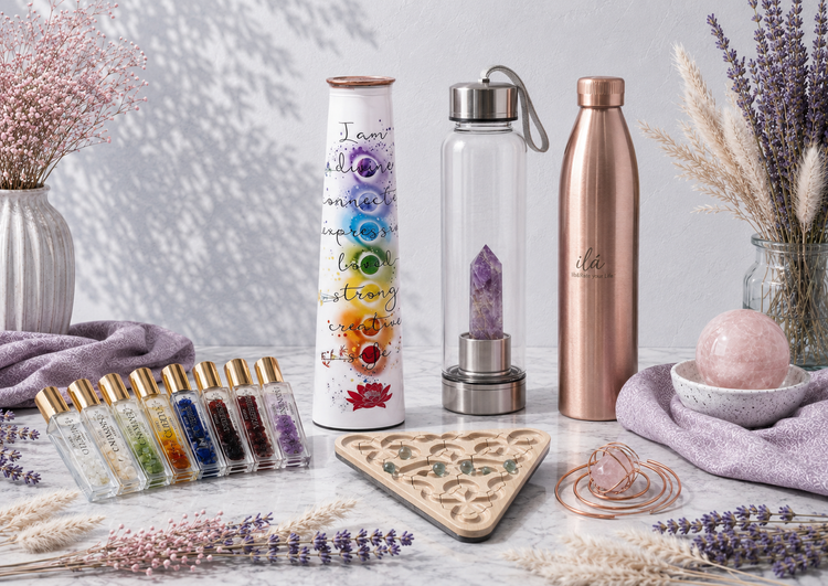 Daily essentials and mindful living collection featuring zodiac perfume oils, an affirmation bottle, crystal-infused water bottle, copper vessel, meditation maze, and rose quartz copper droplet in a bright botanical setting. — for Carpe Diem Dream