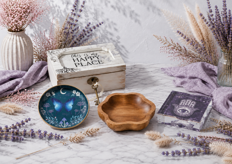 Decorative storage collection featuring a wooden keepsake box, butterfly trinket dish, teak catch-all tray, and Hamsa acrylic dish in a bright botanical setting. — for Carpe Diem Dream