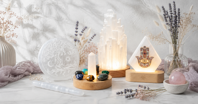 Selenite & Charging Tools collection featuring a selenite lamp, charging plate, spiral wand, crystal charging base, and illuminated Hamsa lamp in a bright botanical studio. — for Carpe Diem Dream
