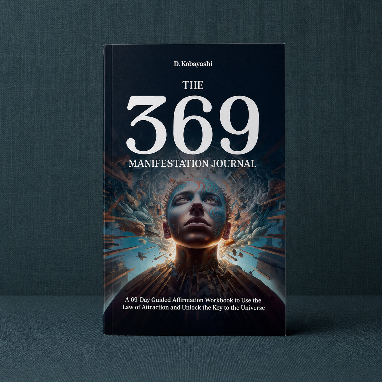 The 369 Manifestation Journal paperback by D. Kobayashi displayed upright on a dark teal linen background featuring a 69-day guided manifestation program with affirmations, reflection prompts, and Law of Attraction exercises for abundance and intentional living — for Carpe Diem Dream