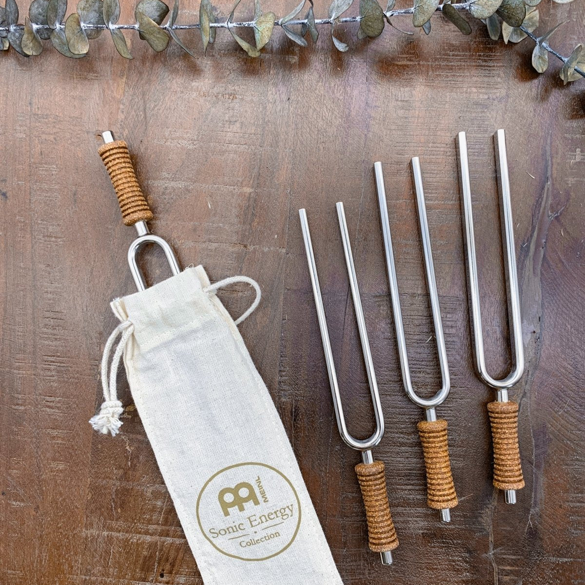 Seven chakra tuning forks with cork handles, a striker, and a cotton storage pouch arranged on a wooden surface. — for Carpe Diem Dream
