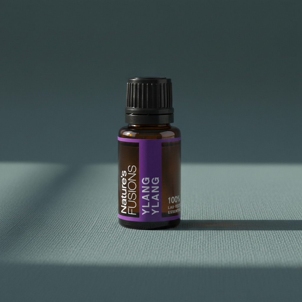 A 15ml amber glass bottle of Ylang Ylang essential oil with a black cap and purple label displayed on a muted teal linen surface with soft natural light. — for Carpe Diem Dream