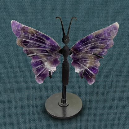 Amethyst crystal butterfly wings on a black stand displayed upright on a deep teal linen background with soft diffused lighting. — for Carpe Diem Dream