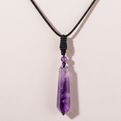 Amethyst crystal pendant on a black cord displayed against a soft textured backdrop with gentle natural lighting. — for Carpe Diem Dream