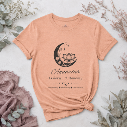 Aquarius Moon I Cherish Autonomy zodiac T-shirt in Heather Peach with black moon-inspired lotus, floral, and celestial artwork and Individuality, Friendship, Perspective text, styled in a cool-toned studio botanical flat lay. — for Carpe Diem Dream