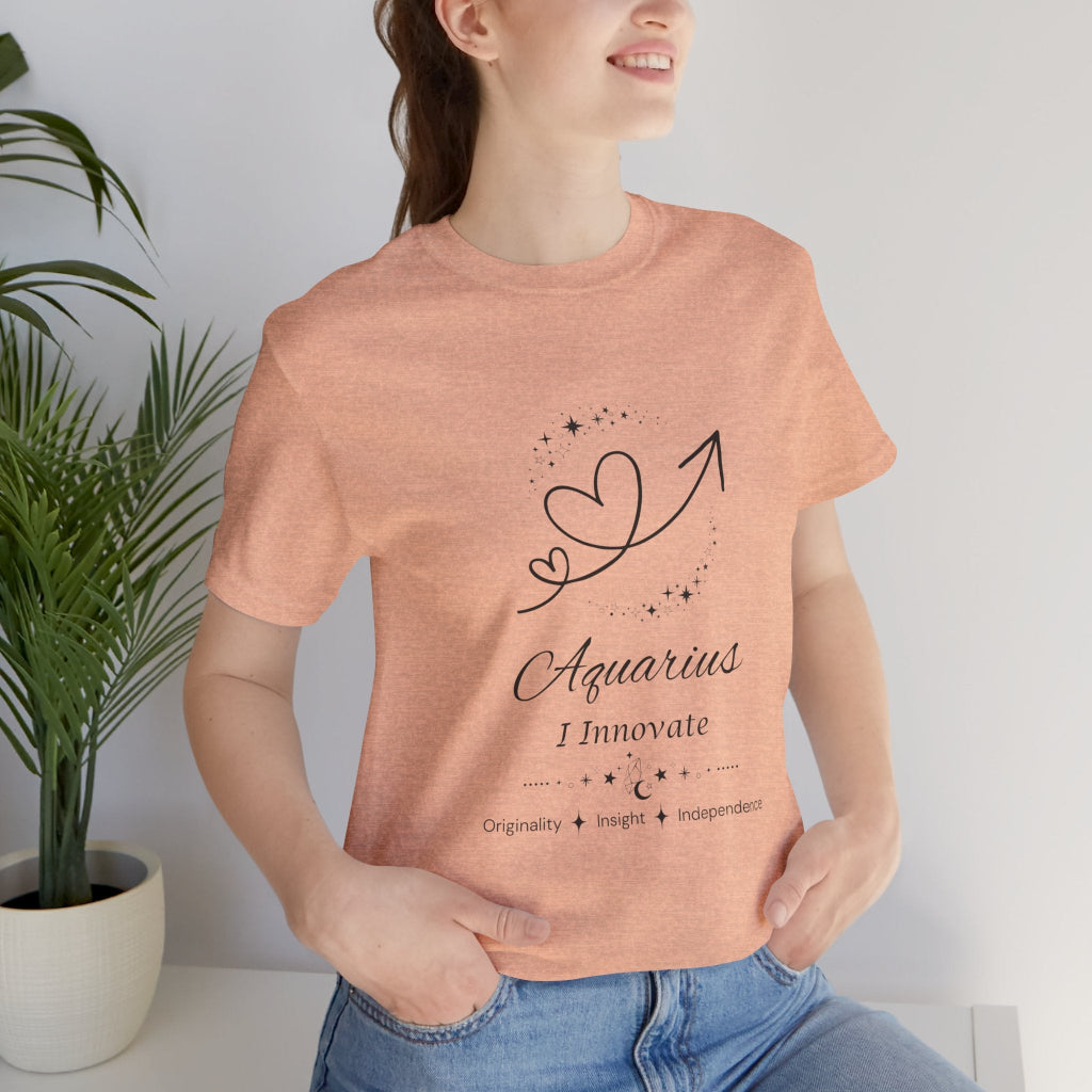 Model wearing a Heather Peach Aquarius Rising I Innovate zodiac T-shirt with black celestial heart and arrow artwork. — for Carpe Diem Dream