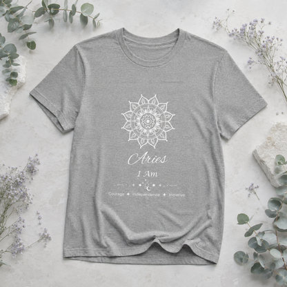 Aries Sun I Am zodiac T-shirt in athletic heather with white sun-inspired mandala artwork and Courage, Independence, Initiative text, styled in a cool-toned studio botanical flat lay. — for Carpe Diem Dream