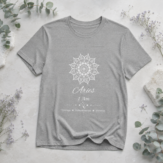Aries Sun I Am zodiac T-shirt in athletic heather with white sun-inspired mandala artwork and Courage, Independence, Initiative text, styled in a cool-toned studio botanical flat lay. — for Carpe Diem Dream