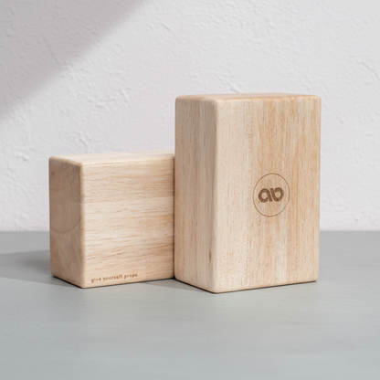 Two natural balsa wood yoga blocks displayed on a gray surface against a textured white wall. — for Carpe Diem Dream