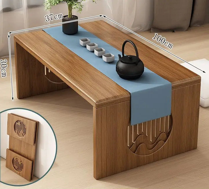 A bamboo folding table in a 100cm size displayed on a wooden floor with a tea setup, showing its natural finish and low-profile design. — for Carpe Diem Dream