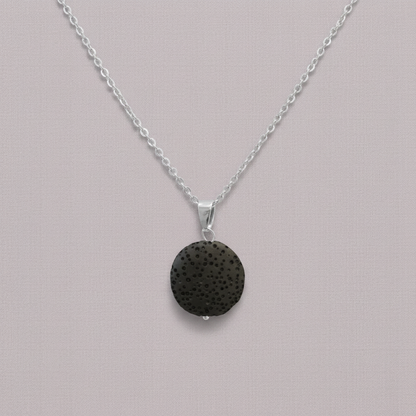 A round black lava stone essential oil necklace on a silver chain displayed against a soft neutral background. — for Carpe Diem Dream