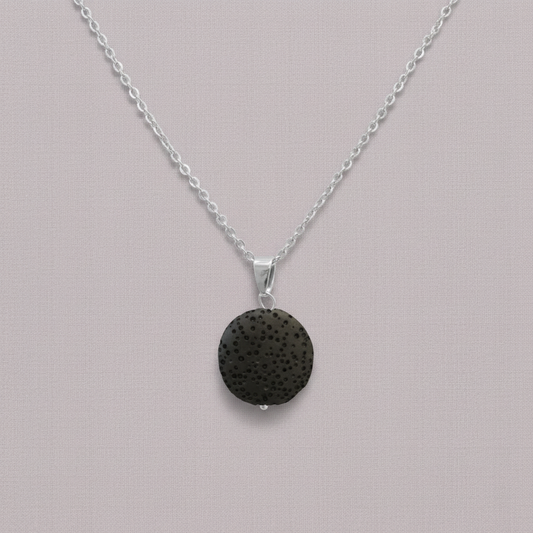 A round black lava stone essential oil necklace on a silver chain displayed against a soft neutral background. — for Carpe Diem Dream
