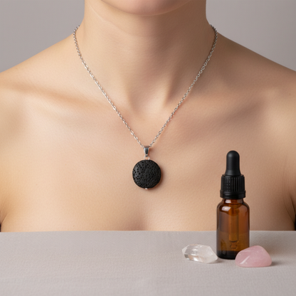 A woman wearing a round black lava stone essential oil necklace beside an amber oil bottle and two small crystals on a neutral surface. — for Carpe Diem Dream