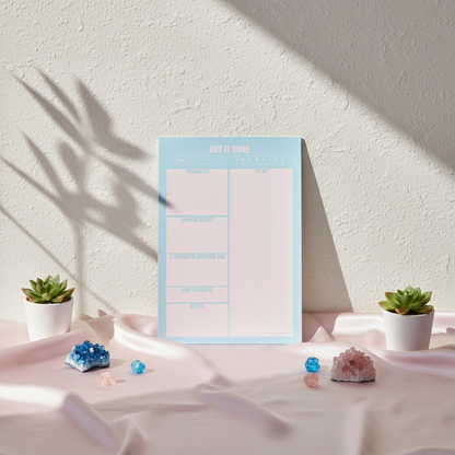 Blue and pink 7x10 daily planner notepad styled upright on blush fabric with crystals and small plants in soft natural light — for Carpe Diem Dream