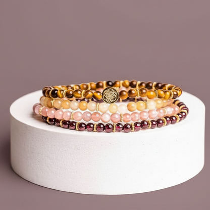 Stacked gemstone bracelet set displayed on a white travertine cylinder against a muted mauve backdrop. — for Carpe Diem Dream