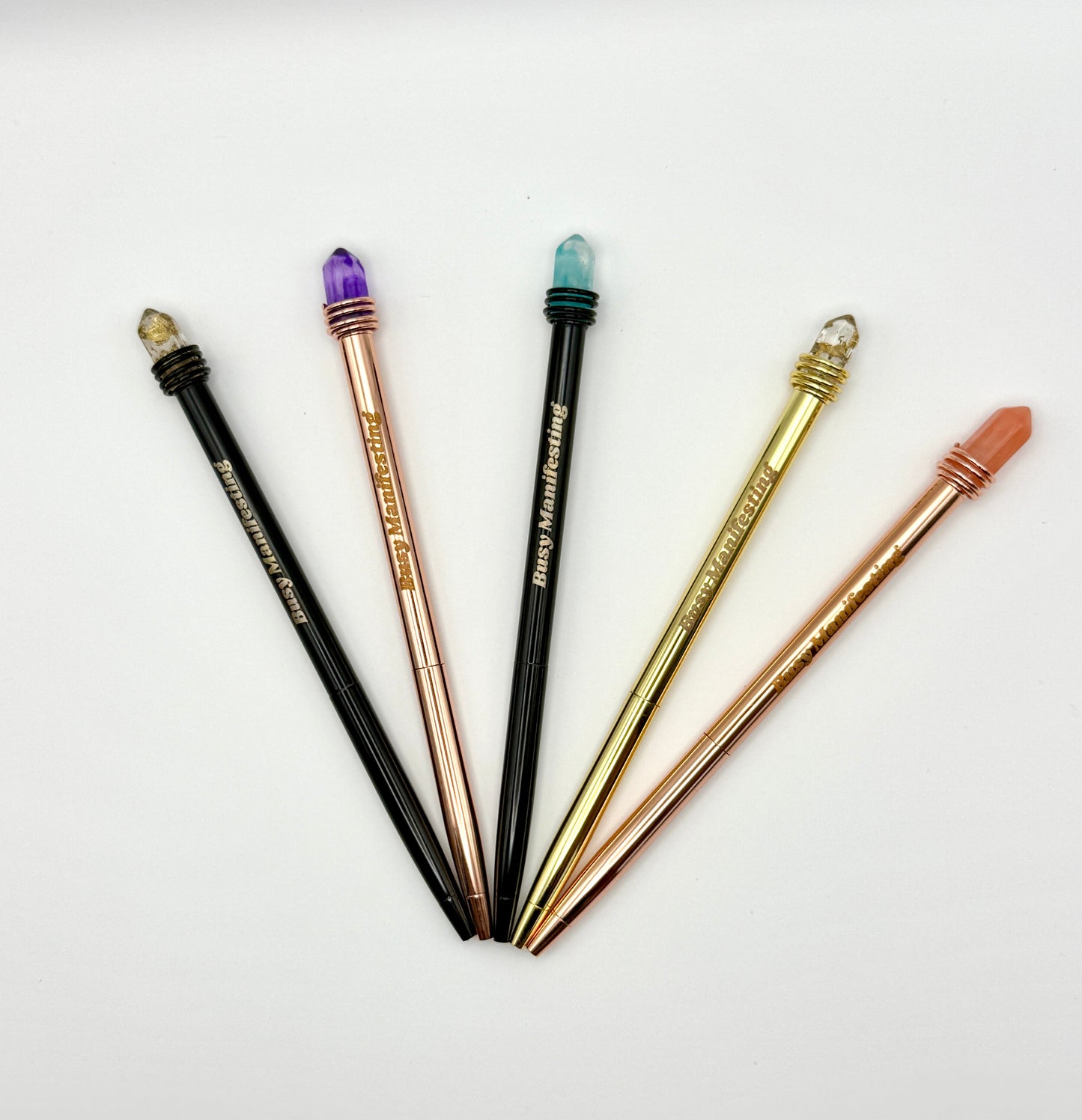 Metallic Busy Manifesting crystal mystic pens with faux crystal tops displayed in a full fan arrangement on white background — for Carpe Diem Dream