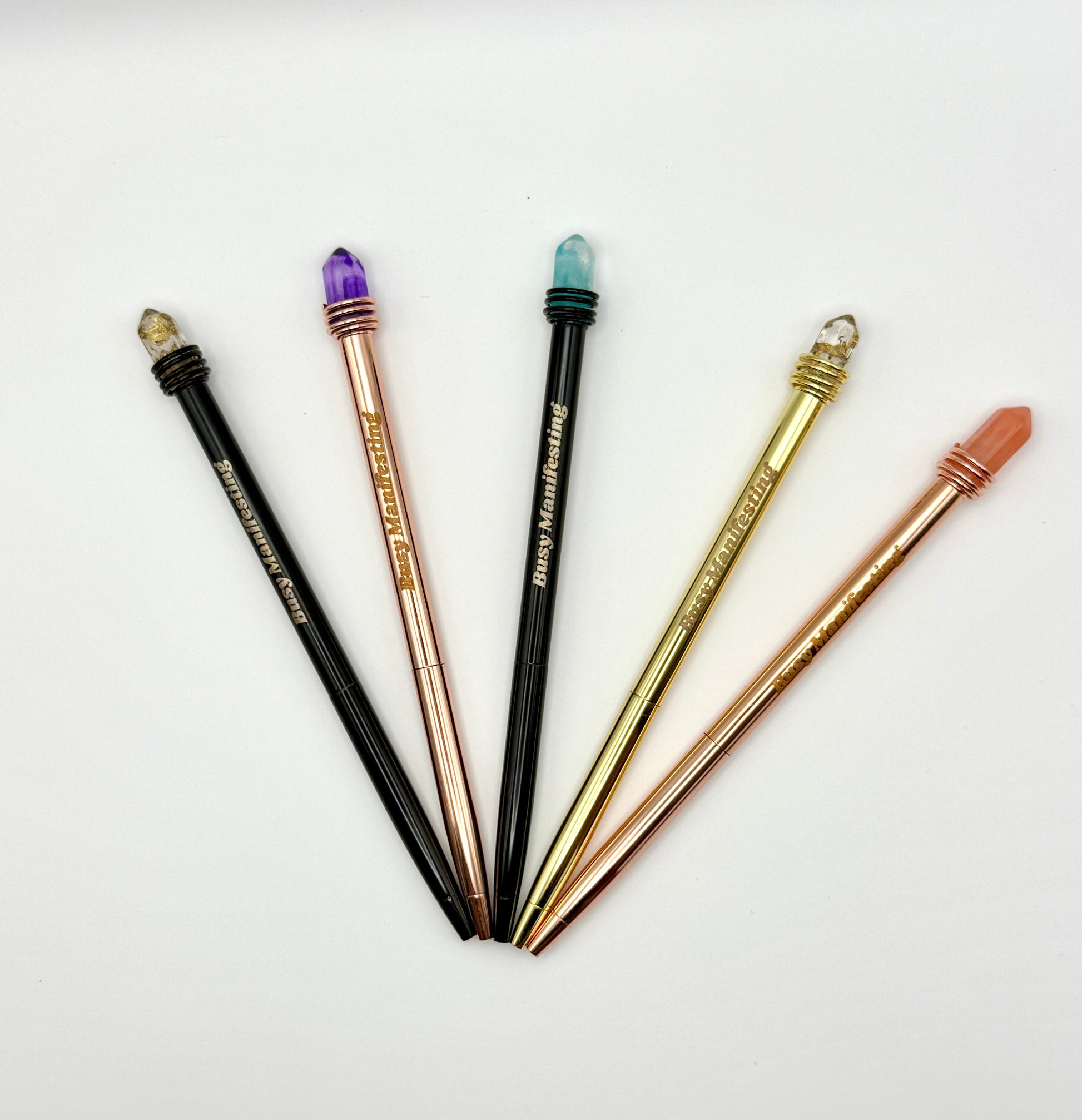 Metallic Busy Manifesting crystal mystic pens with faux crystal tops displayed in a full fan arrangement on white background — for Carpe Diem Dream