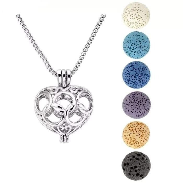 A silver heart-shaped cage diffuser necklace displayed on a white background with six interchangeable lava stone beads arranged vertically beside it. — for Carpe Diem Dream