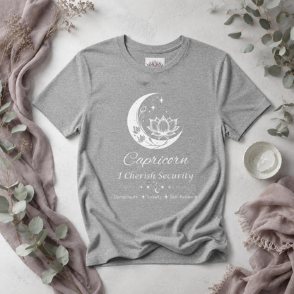 Capricorn Moon I Cherish Security zodiac T-shirt in Athletic Heather with white moon-inspired lotus, floral, and celestial artwork and Composure, Loyalty, Self-Reliance text, styled in a cool-toned studio botanical flat lay. — for Carpe Diem Dream