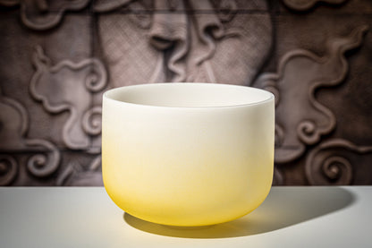 Yellow gradient frosted quartz crystal singing bowl representing the solar plexus chakra displayed on a white surface with decorative carved background — for Carpe Diem Dream