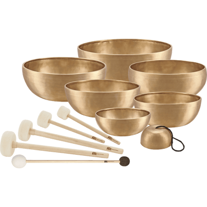 Seven handcrafted bronze singing bowls with five wooden-handled mallets, felt rings, and protective covers arranged as a complete chakra sound healing set on a transparent background. — for Carpe Diem Dream