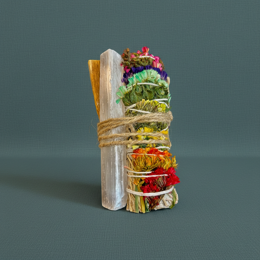 A chakra sage smudge bundle tied with twine beside a Palo Santo stick and a raw selenite wand standing upright on a muted teal background. — for Carpe Diem Dream