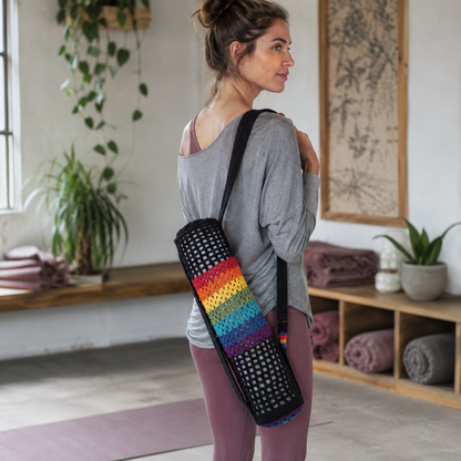 A person carries a black crochet chakra yoga mat bag with rainbow stripes over one shoulder in a cool natural-light yoga studio with mauve mats and plants. — for Carpe Diem Dream
