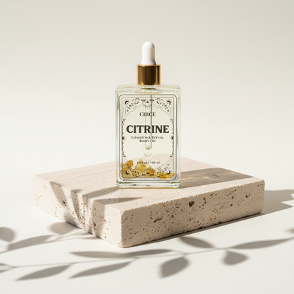Citrine Ritual Body Oil glass dropper bottle displayed on a travertine pedestal with soft botanical shadows. — for Carpe Diem Dream