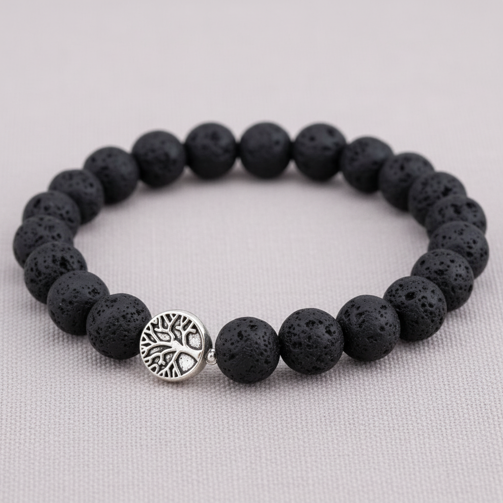 A close-up of a black lava stone stretch bracelet featuring textured porous beads and a silver Tree of Life charm on a textured linen background. — for Carpe Diem Dream
