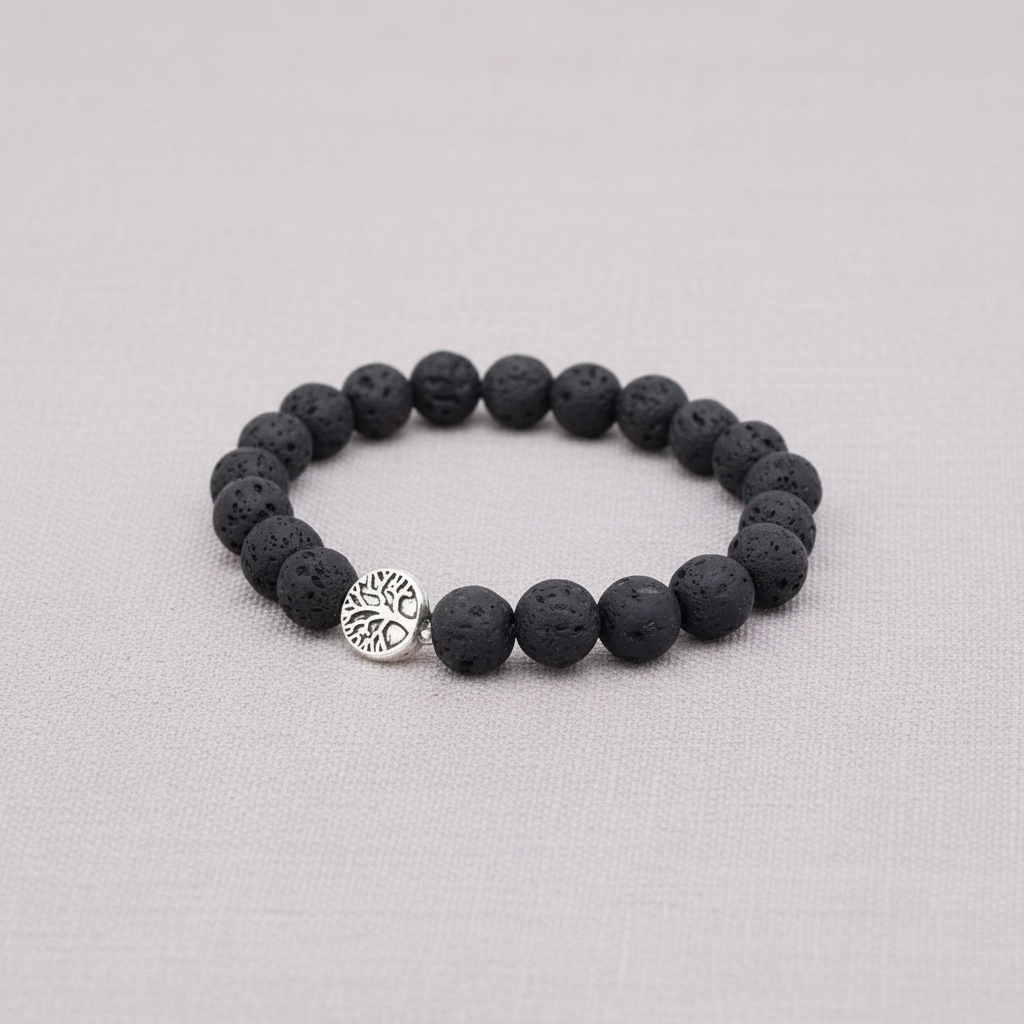 A black lava stone stretch bracelet with a silver Tree of Life charm displayed on a textured linen background. — for Carpe Diem Dream