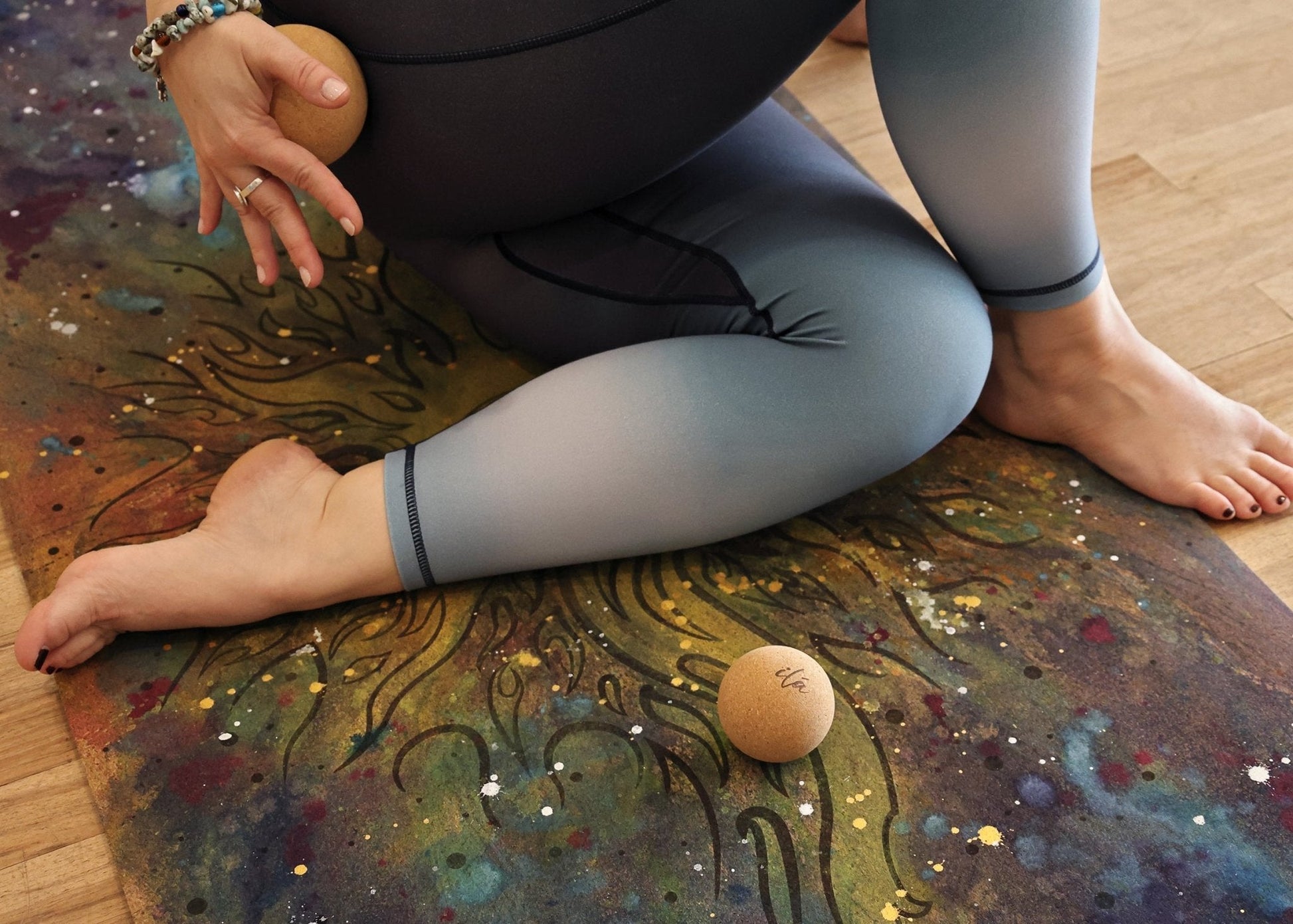 Small and large cork yoga massage balls displayed on a patterned yoga mat during a seated wellness recovery session. — for Carpe Diem Dream