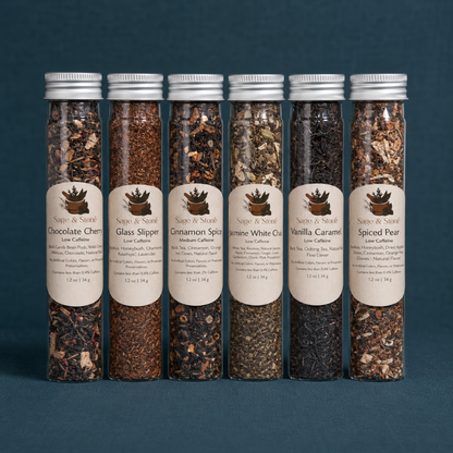 Cozy Winter Tea Sampler tubes with labeled seasonal tea blends on a dark teal linen backdrop. — for Carpe Diem Dream