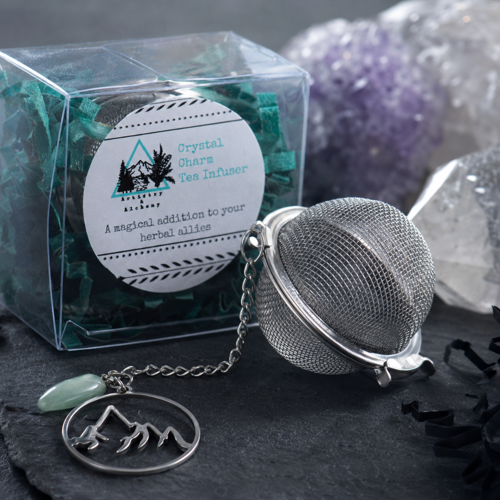 Crystal Charm Tea Infuser – close-up detail image highlighting the metal mesh tea ball, chain, mountain charm, crystal accent, clear packaging, and textured materials on a dark slate surface with cool diffused daylight and premium commercial styling. — for Carpe Diem Dream
