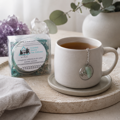 Crystal Charm Tea Infuser – authentic tea infuser shown in a peaceful tea ritual with a neutral ceramic mug, crystal charm detail, clear packaging, natural stone, soft linen, and cool diffused daylight. The product supports a calm, intentional loose-leaf tea experience. — for Carpe Diem Dream