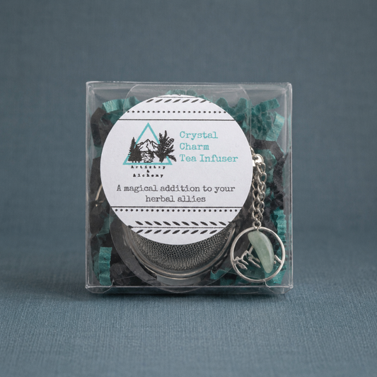 Crystal Charm Tea Infuser – authentic packaged tea infuser displayed on a dark teal textured linen backdrop with a matching linen surface, photographed in cool diffused daylight with soft natural shadows and premium commercial styling. The product remains the sole focal point with no props or additional objects. — for Carpe Diem Dream