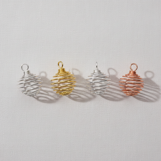A set of silver, gold, and copper spiral crystal cage pendants displayed upright on a neutral textured background. — for Carpe Diem Dream