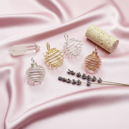 A set of silver, gold, and copper spiral crystal cage pendants arranged on a soft blush satin surface with a clear quartz point and lavender sprigs. — for Carpe Diem Dream