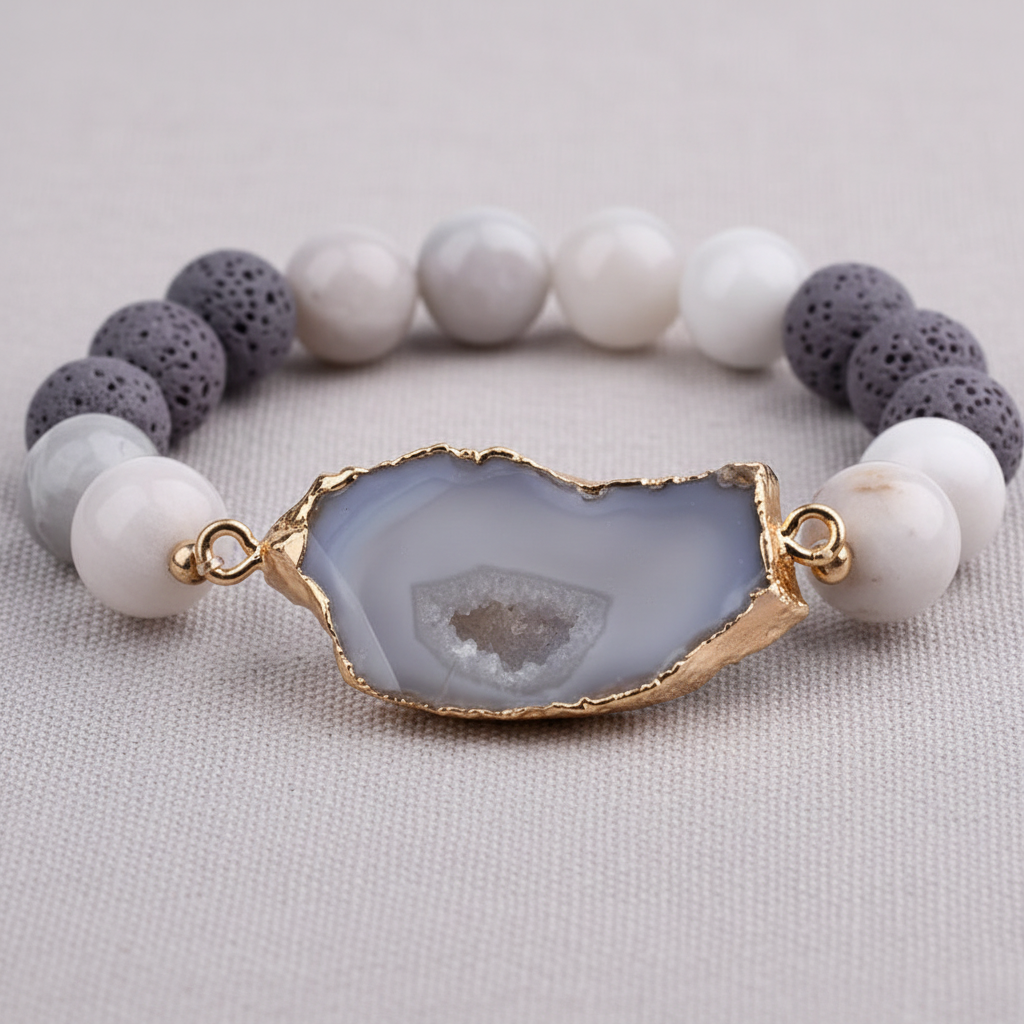 A close-up of a crystal and gold lava stone stretch bracelet featuring a gold-edged center stone and porous lava beads on a textured linen background. — for Carpe Diem Dream