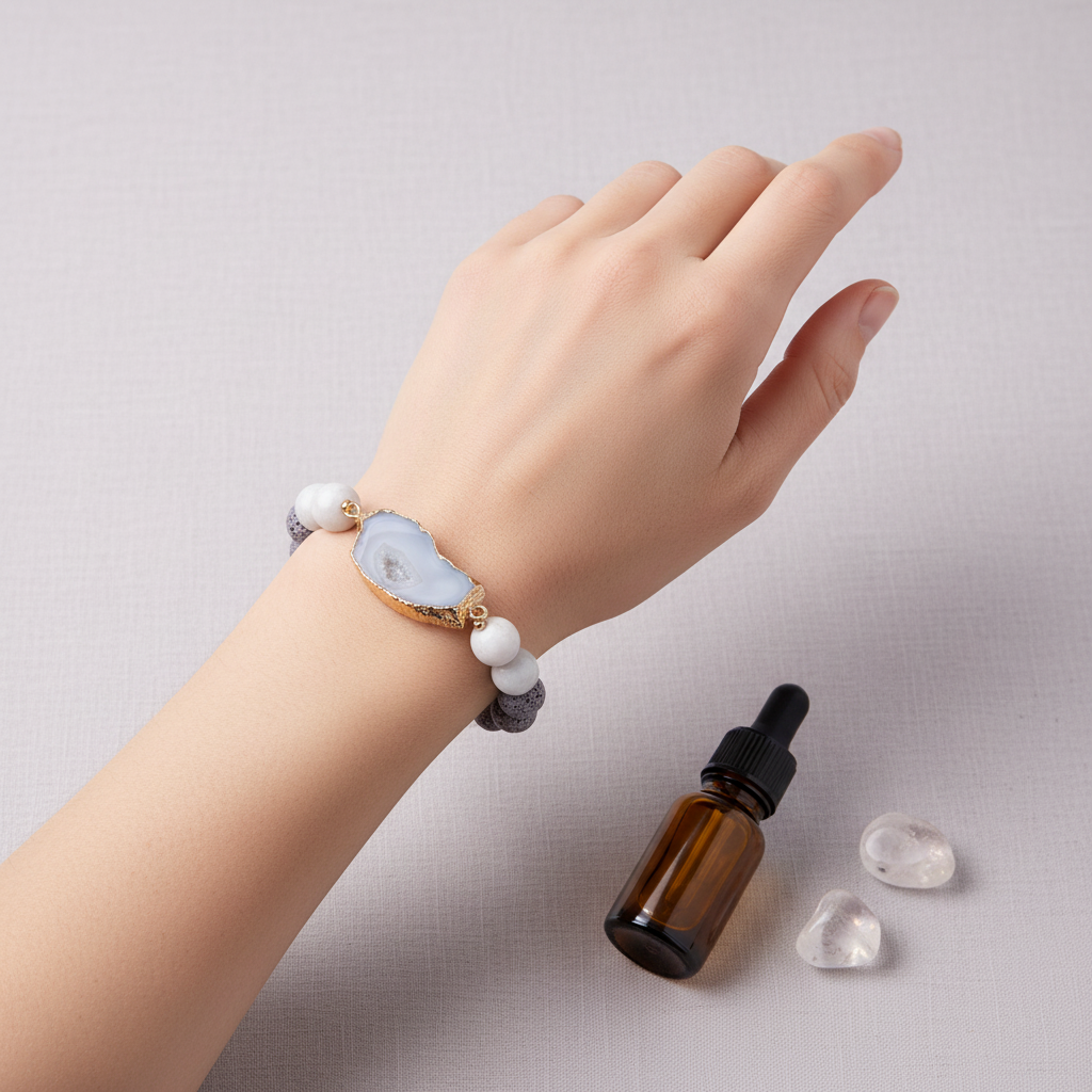 A crystal and gold lava stone stretch bracelet worn on a wrist beside an amber essential oil bottle and small clear crystals on a textured linen background. — for Carpe Diem Dream