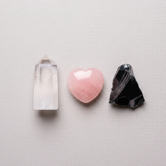 Clear quartz point, pink rose quartz heart, and raw black obsidian magnet displayed on a soft textured surface. — for Carpe Diem Dream