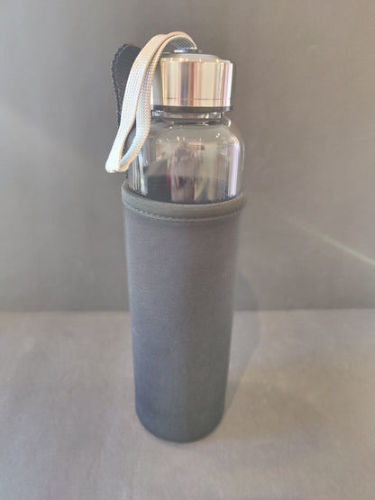 A crystal infused glass water bottle with a stainless steel cap and gray insulation sleeve standing upright against a neutral backdrop. — for Carpe Diem Dream