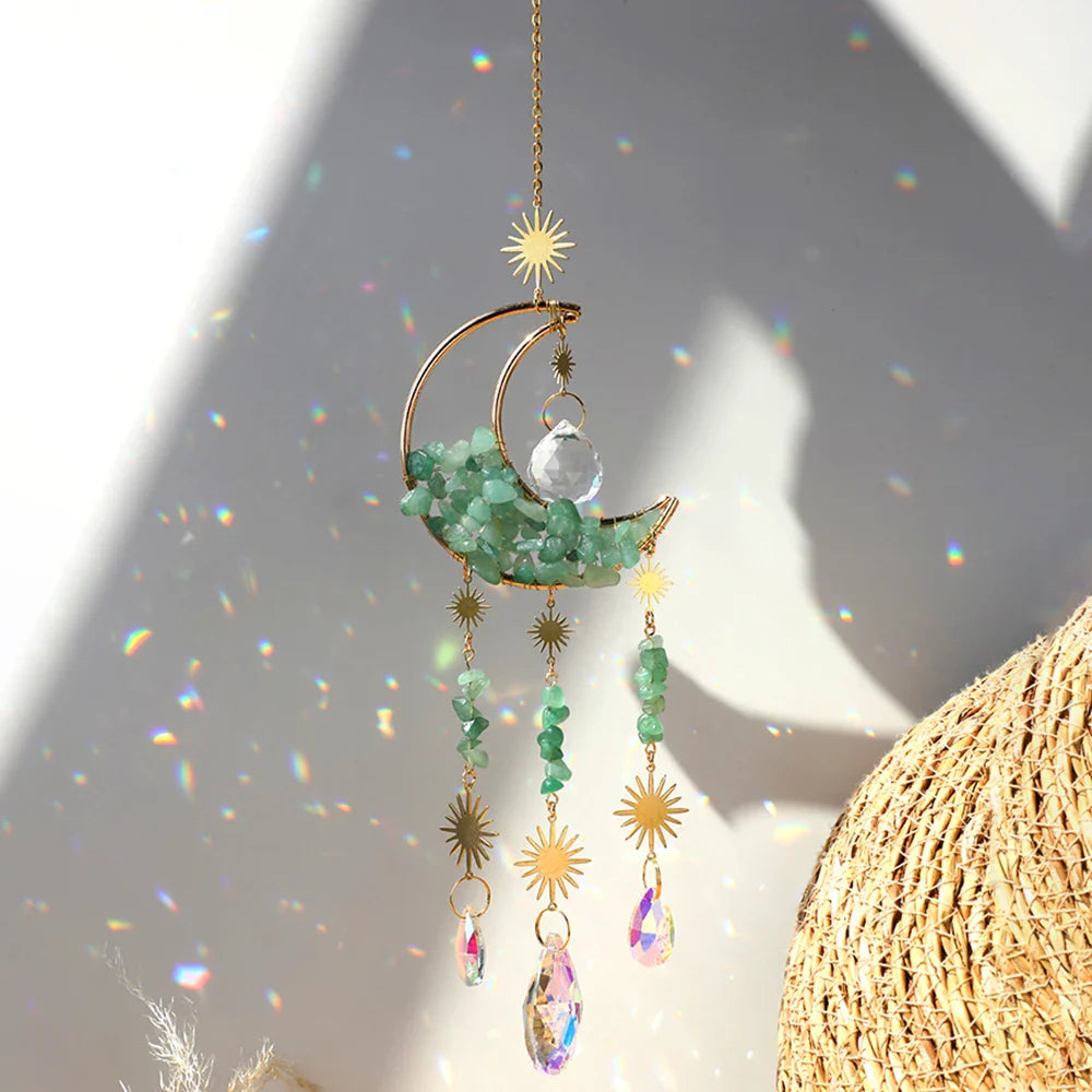 A green aventurine crystal moon suncatcher with a gold crescent frame, polished green stone chips, and hanging prism drops displayed in bright natural sunlight with vivid rainbow reflections and soft shadows. — for Carpe Diem Dream