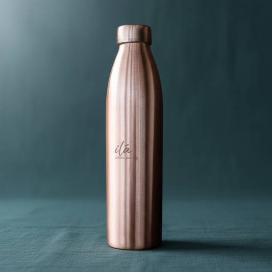 Tall brushed copper Ayurvedic water vessel displayed upright on deep teal textured linen with soft natural lighting. — for Carpe Diem Dream