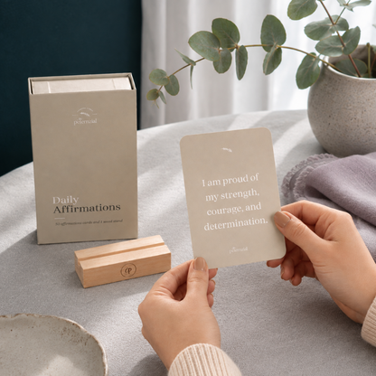 Hands holding a daily affirmation card beside the storage box and wooden stand in a cool-toned mindful setting — for Carpe Diem Dream.