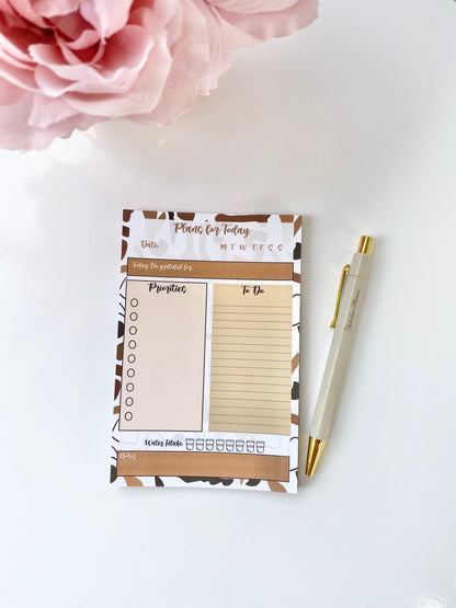 Minimalist 4x6 daily planning sticky notepad with priority and checklist sections shown on a white surface with a gold pen and pink flower accent. — for Carpe Diem Dream