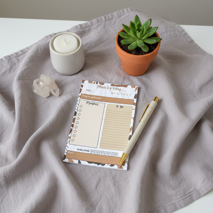 Minimalist 4x6 daily planning sticky notepad with priority and checklist sections resting on draped neutral fabric beside a candle, potted succulent, and clear crystal in soft natural light. — for Carpe Diem Dream